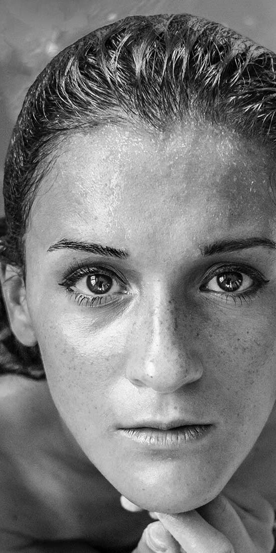 Black-and-white close-up of a woman's face with intense eyes.