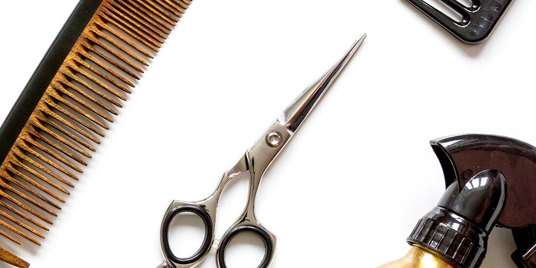Hairdressing tools including scissors, combs, and spray bottle on white background.