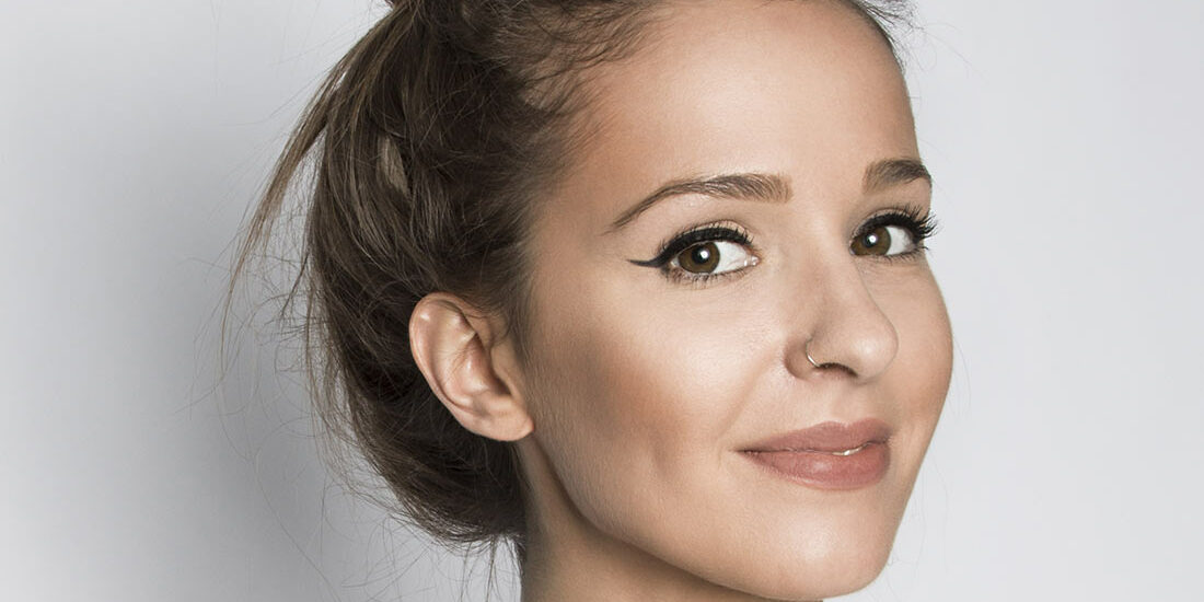 Portrait of a confident woman with a neat bun and subtle makeup.